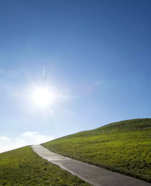 55314-sun-shining-over-paved-road-on-grassy-hillsi-2025-04-04-12-42-06-utc